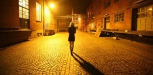 Young woman walking in vacant alley at night